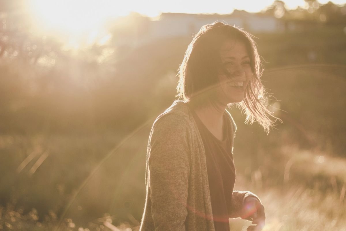 Woman smiling outdoors in sunlight, symbolising emotional wellbeing, balanced gut health, and healthy zinc levels.