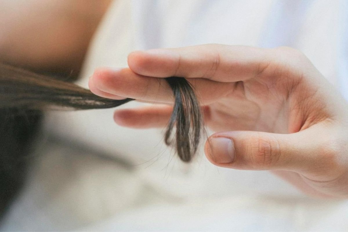 Woman inspecting thinning hair while noticing possible hair loss causes linked to stress, hormones, scalp health, and overall wellbeing.