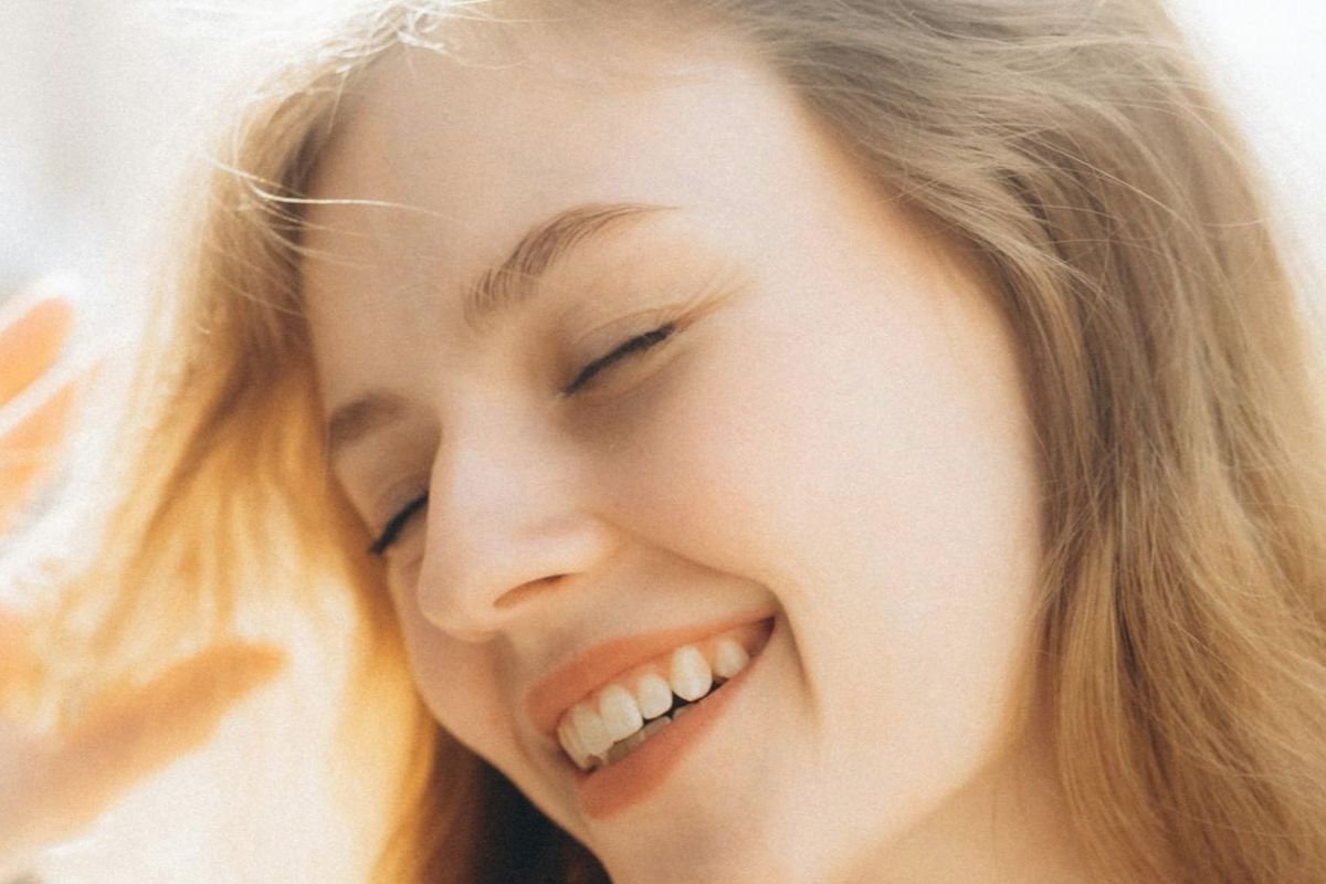Smiling woman with healthy shiny hair representing healthy hair growth, emotional wellbeing, confidence, and overall physical health.