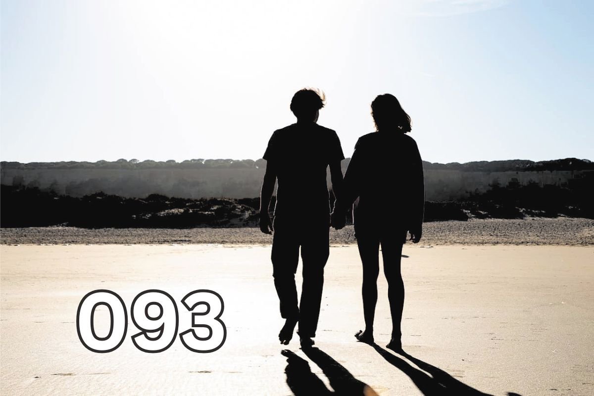 Couple holding hands while walking barefoot on a beach, symbolising growing old together and lifelong companionship.