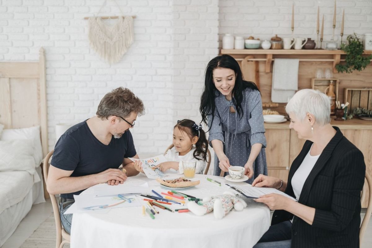 Grandmother sharing a meal with her adult son, daughter-in-law, and grandchild, representing healthy family boundaries and multigenerational living.