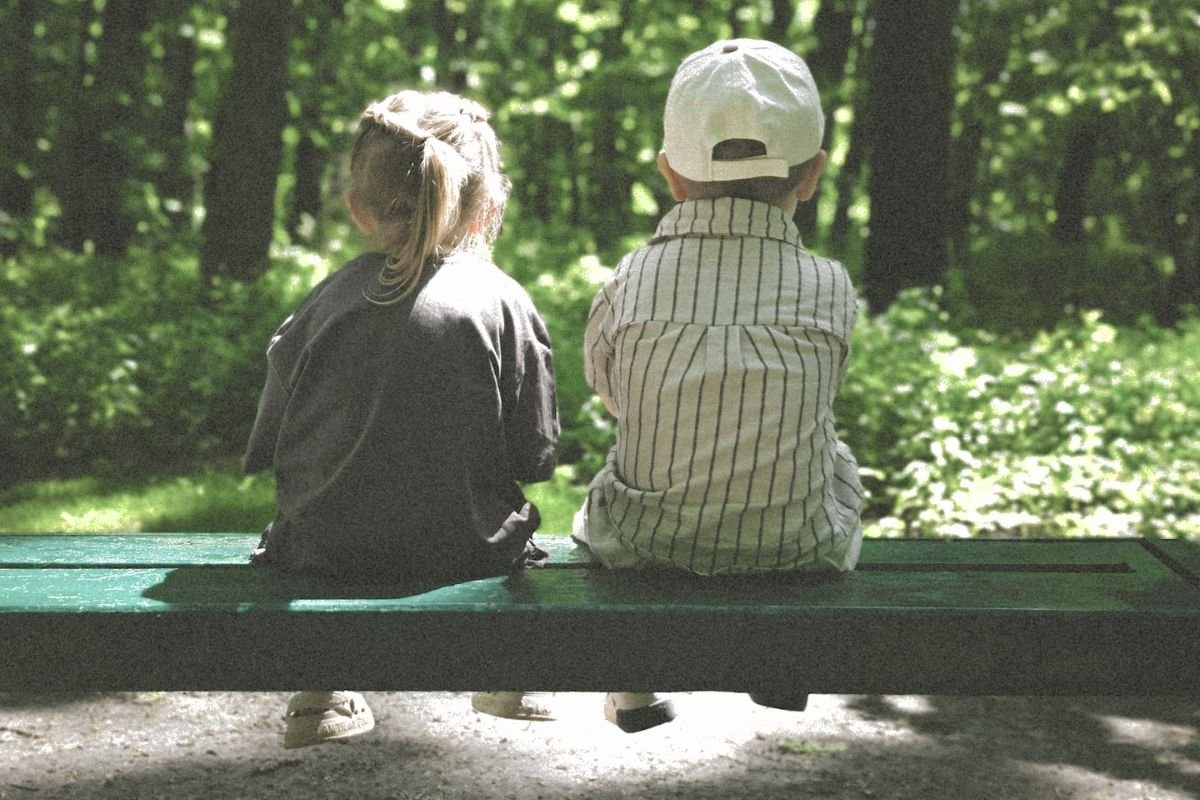 Two children sitting together on a bench, symbolising how childhood wounds and emotional patterns can influence adult relationships.