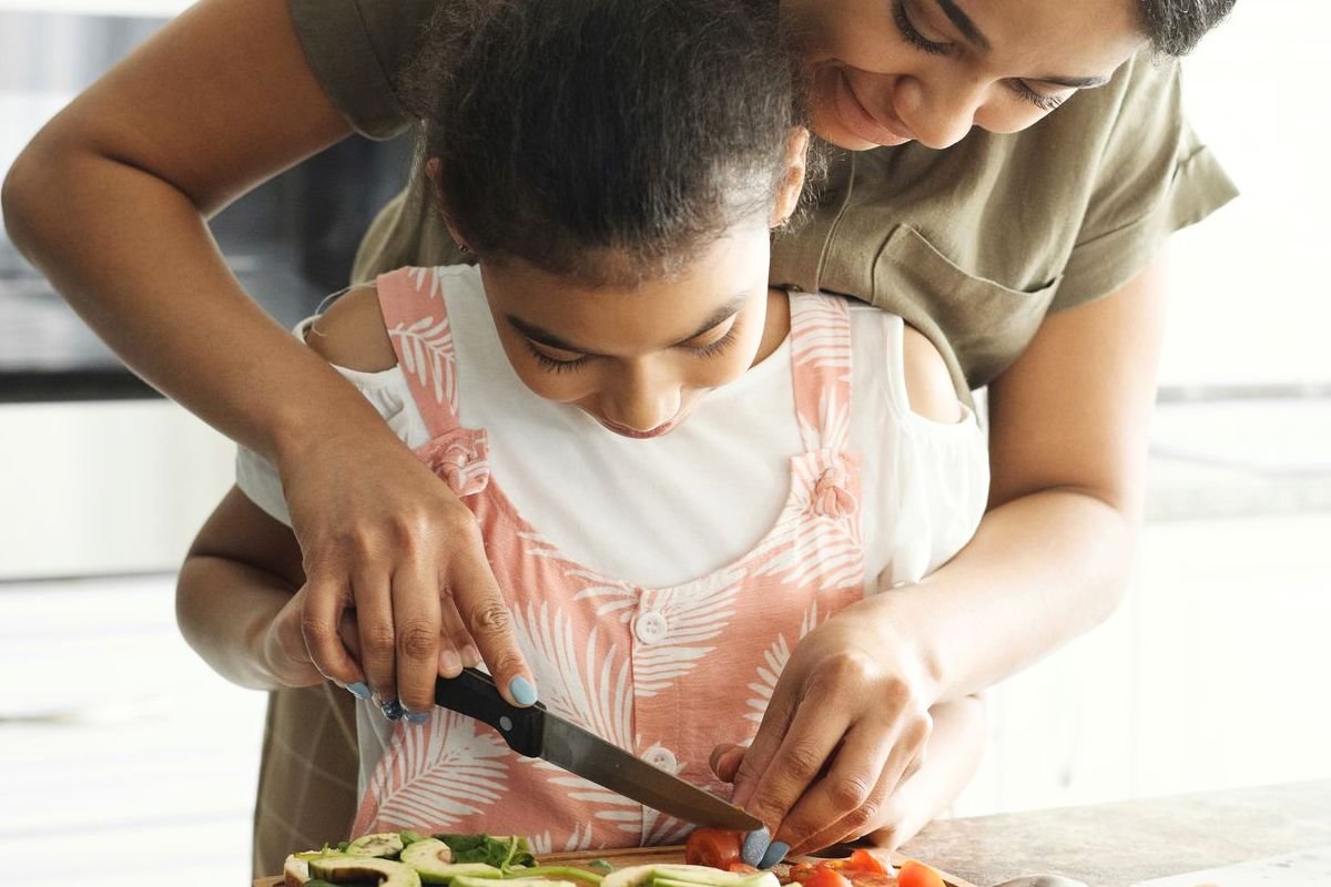 Mother teaching her daughter to prepare vegetables, showing how healthy eating and foods for brain health become lifelong family habits.