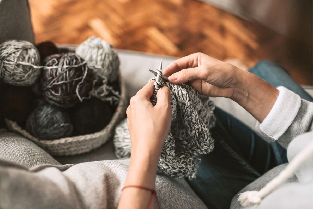 Person knitting peacefully at home, embracing solitude through a relaxing and meaningful hobby.
