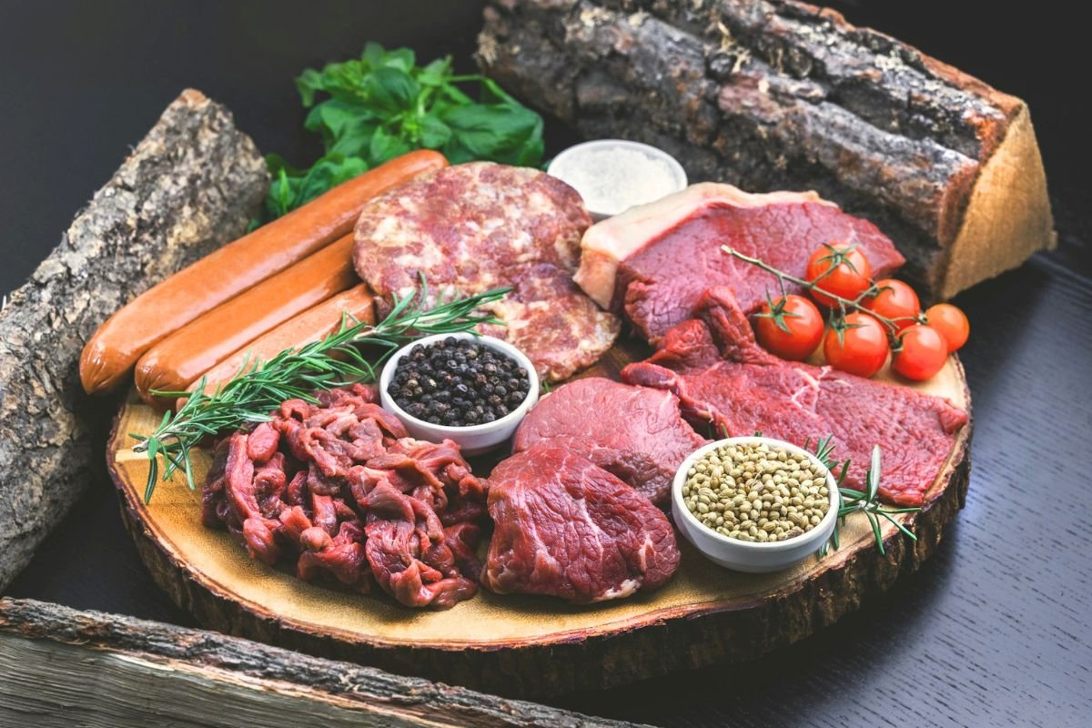 Raw red meat and sausages on a plate, illustrating foods to limit as part of a healthy brain diet that supports long-term brain health.