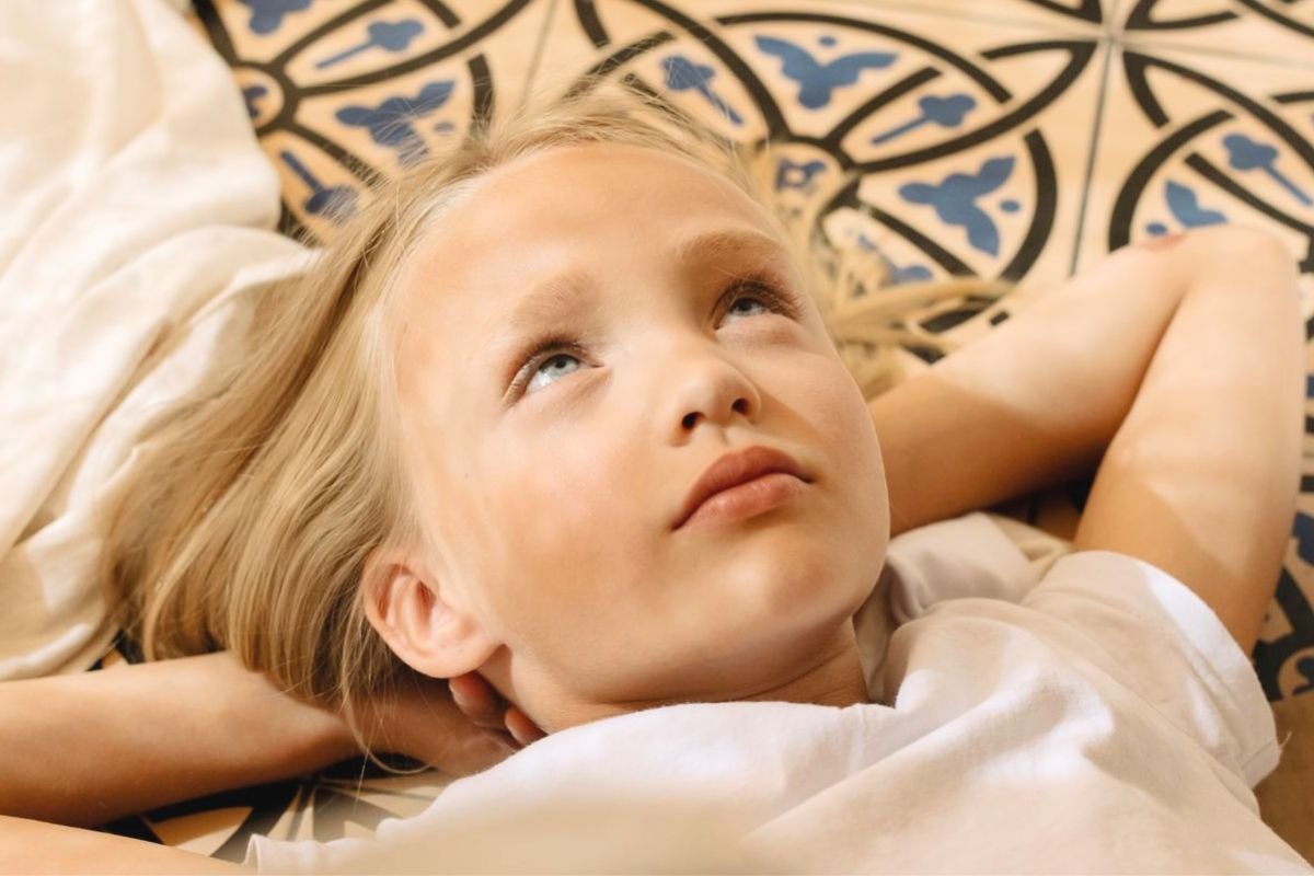 Young girl lying down deep in thought, illustrating self-reflection and the hidden emotional reasons behind behaviour.