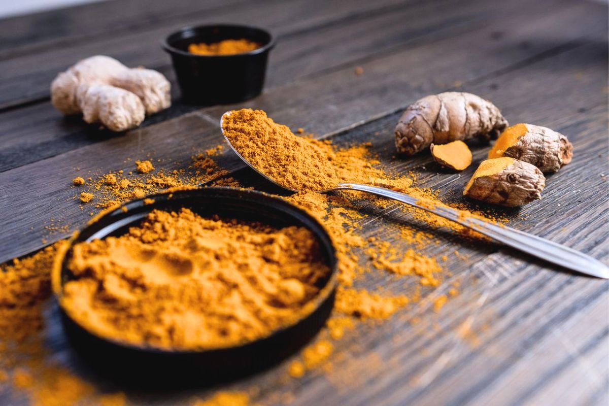 Turmeric root and turmeric powder on a wooden surface, highlighting the natural source of curcumin and its role in nutrition research.