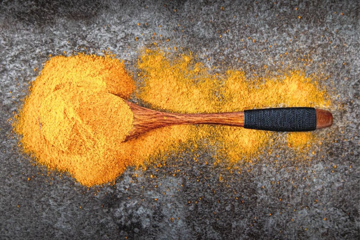 Turmeric powder in a wooden spoon, representing curcumin research into mood support, neurotransmitters, and emotional wellbeing.