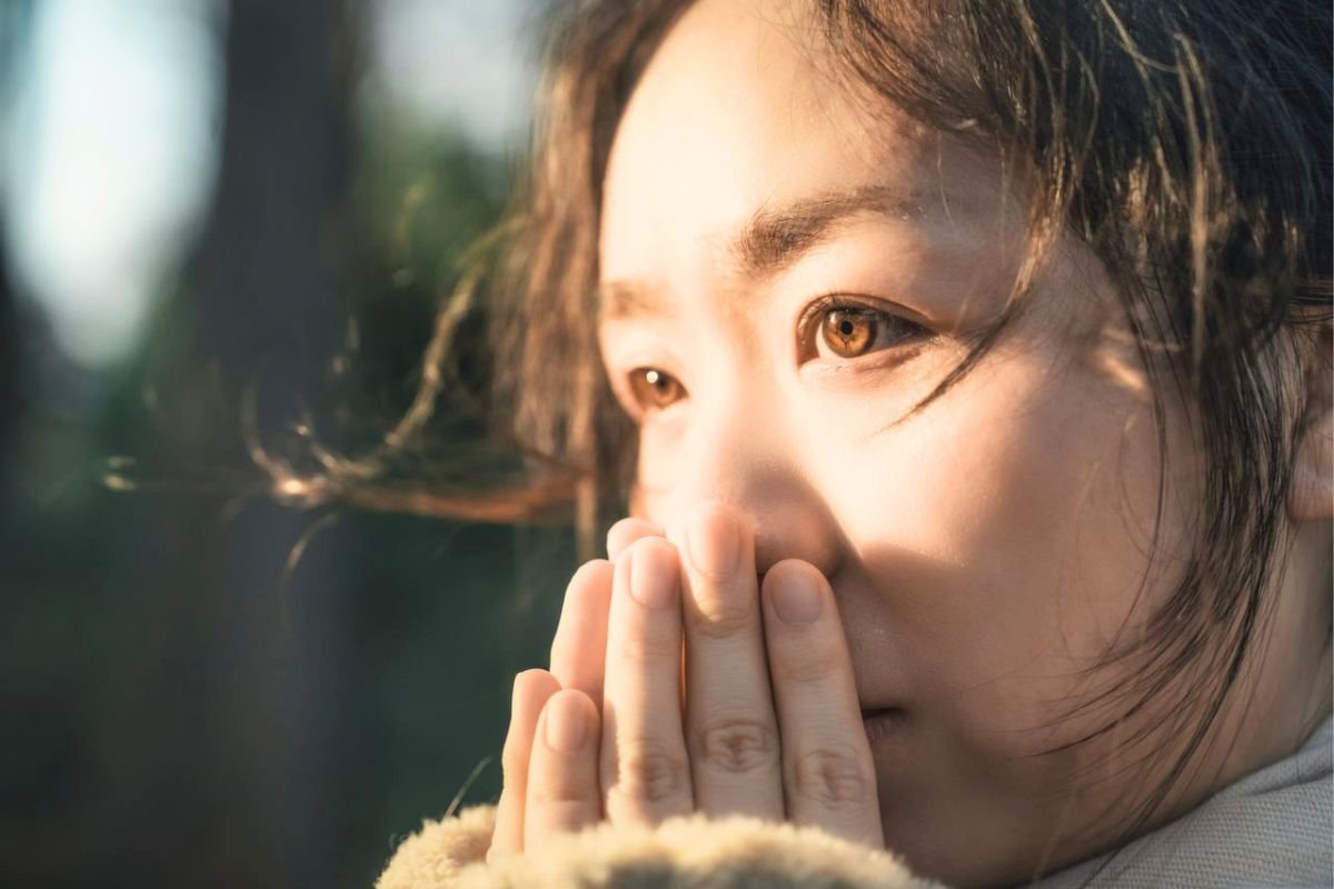 Anxious woman holding her hands near her mouth, illustrating common social anxiety symptoms such as fear, overthinking, and self-consciousness.