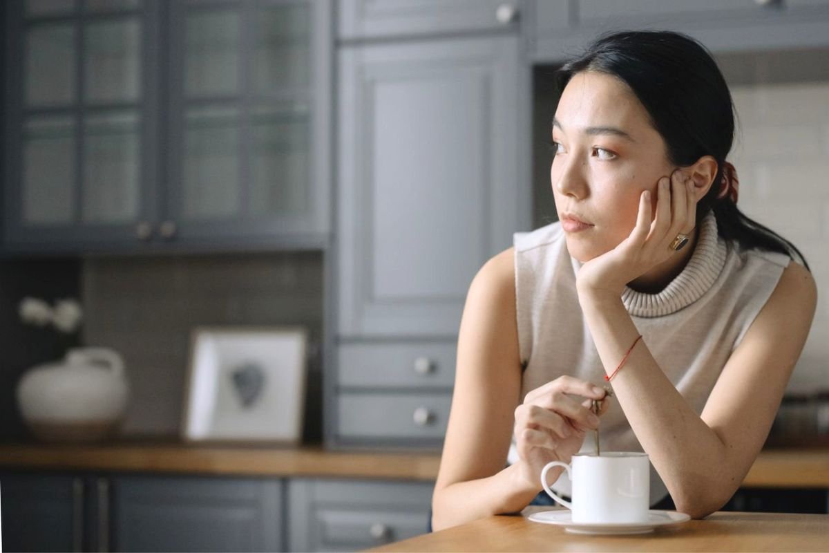 Thoughtful woman sitting alone with a drink, representing the difference between social anxiety and introversion.