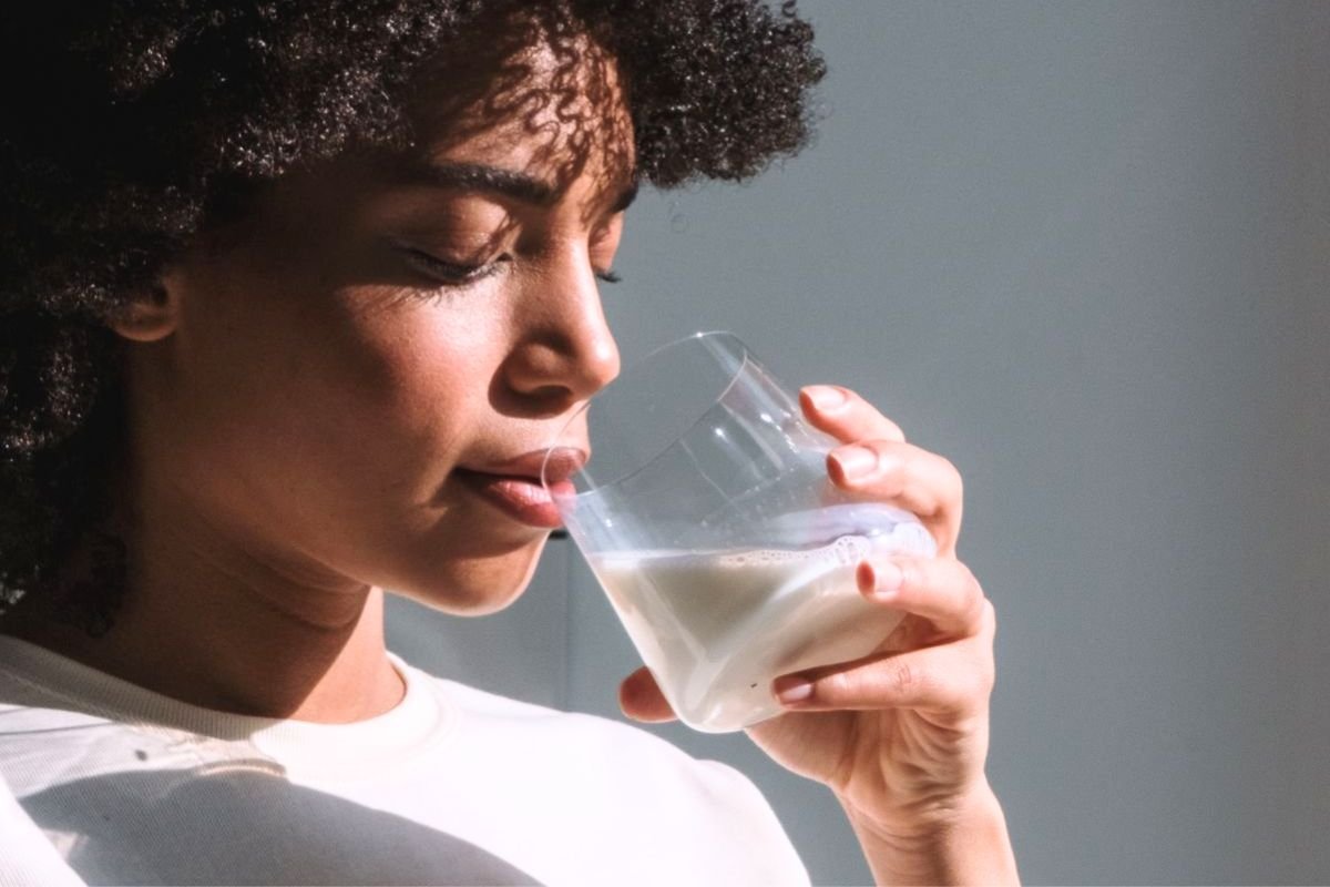 Woman drinking milk as part of a calcium-rich diet