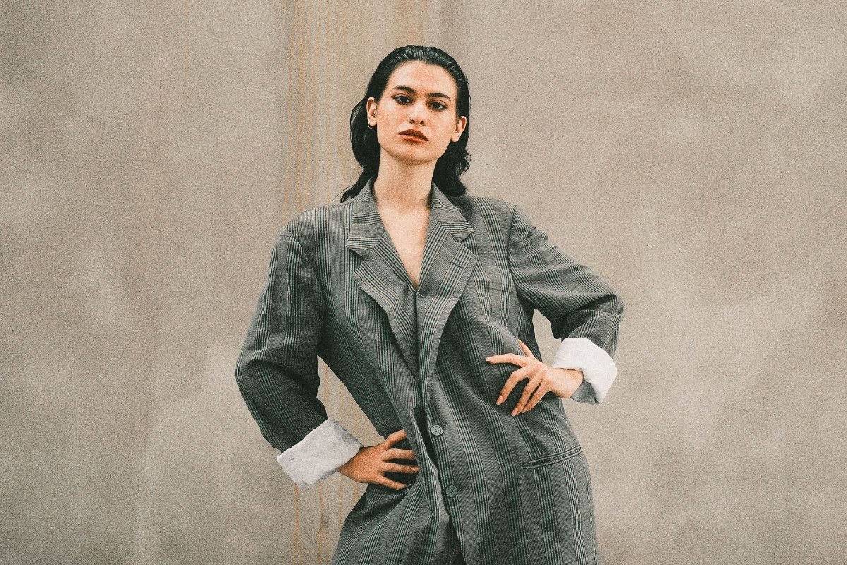 Woman posing outdoors in an oversized grey suit