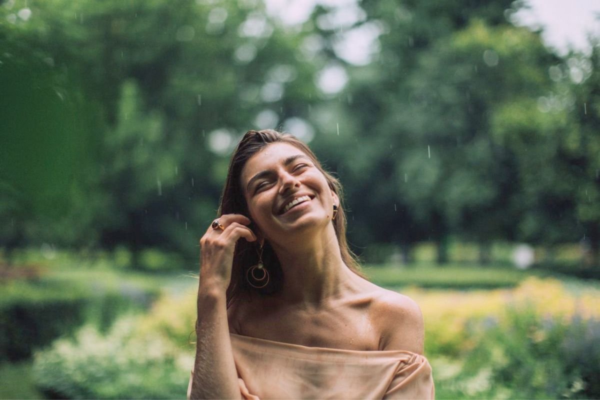 Woman smiling in the rain, symbolising emotional independence, resilience, self-reliance, and finding joy through personal growth.