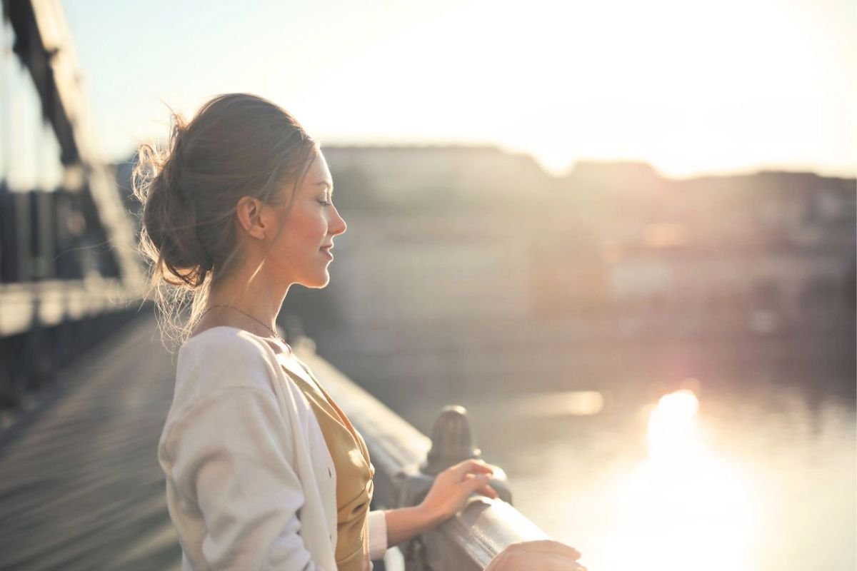 Woman facing the sunrise with her eyes closed and a content expression
