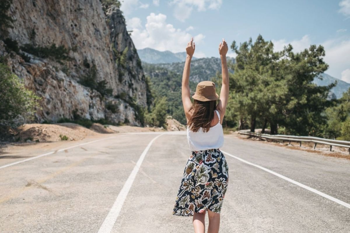 Woman walking freely along a country road, representing emotional independence, healthy boundaries, and confidence after overcoming people pleasing.