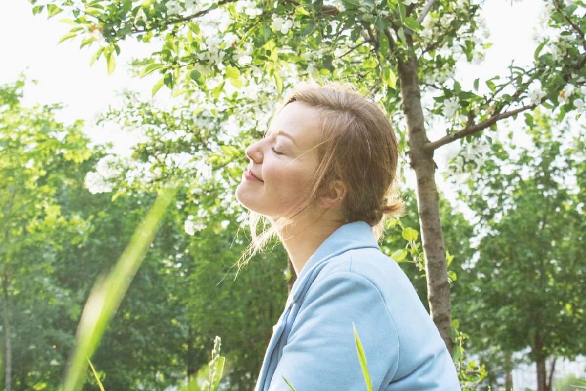 Woman sitting on grass outdoors and taking a relaxing breath