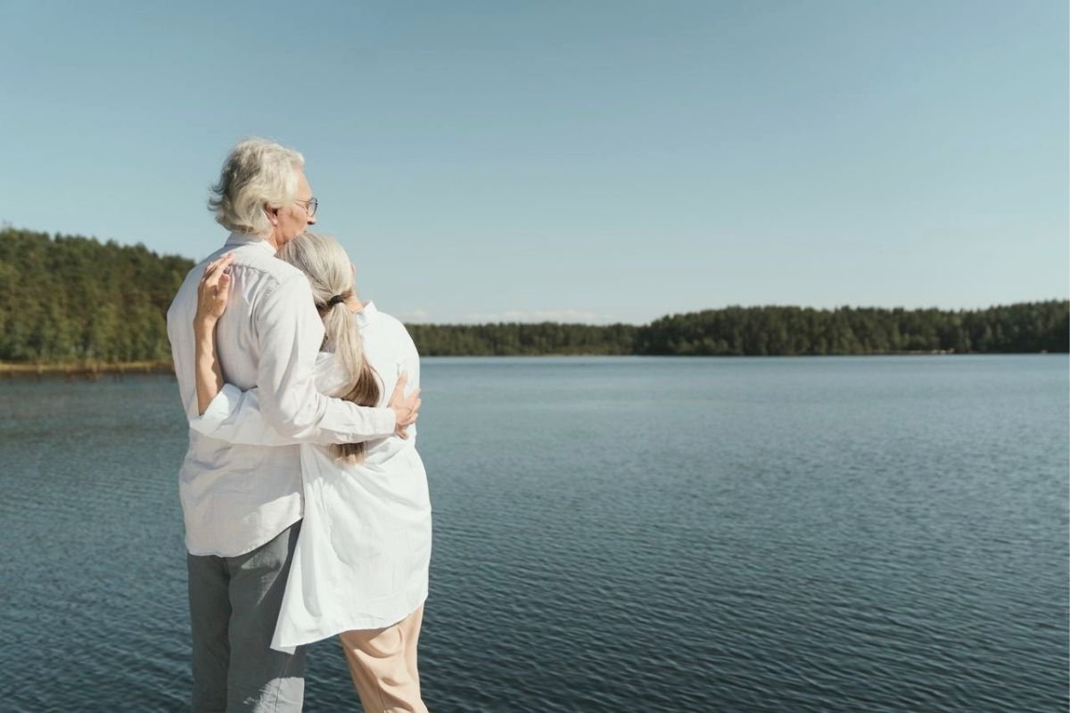 Older couple embracing while looking across a peaceful lake
