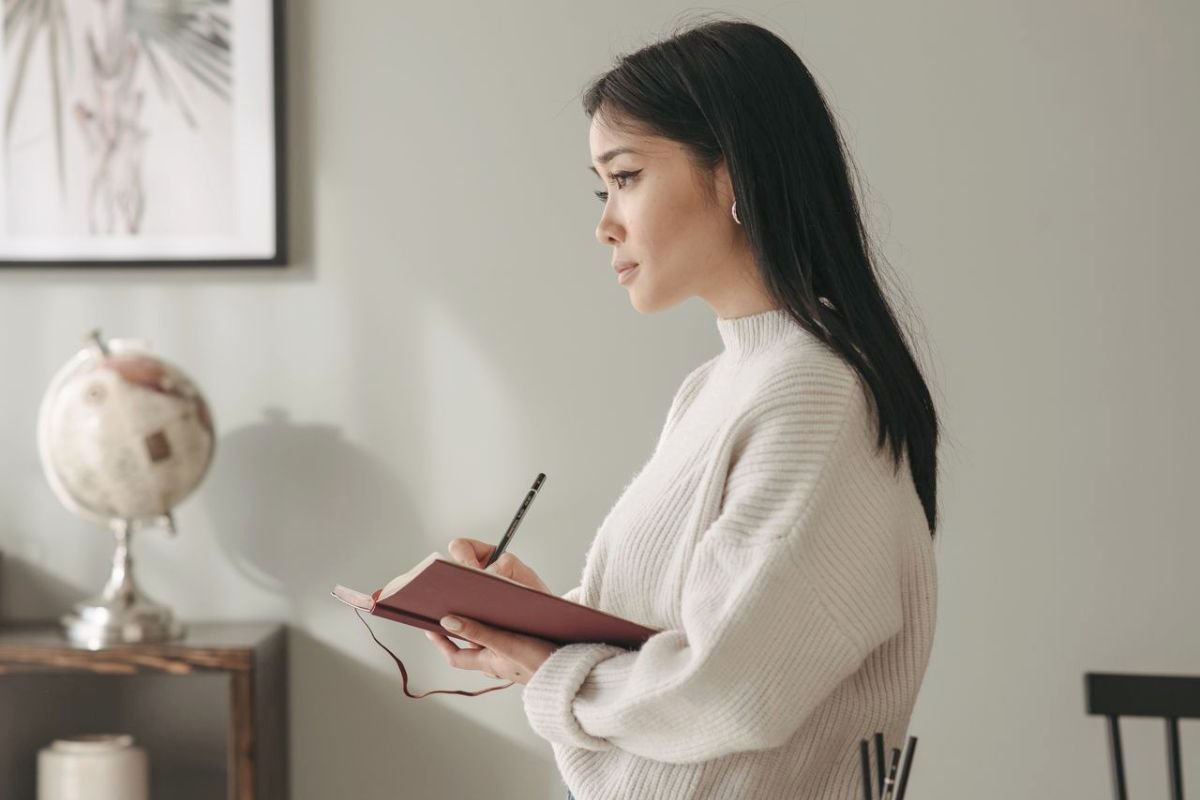 Woman holding a notebook and pen while writing