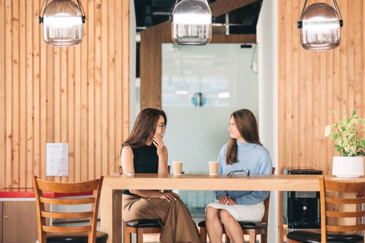 Two friends having a casual conversation over coffee in a cafe