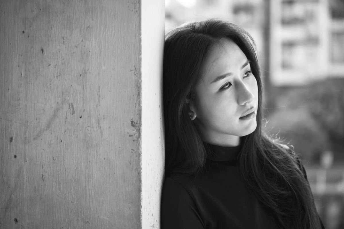 Tired-looking woman leaning against a wall after emotional relationship conflict